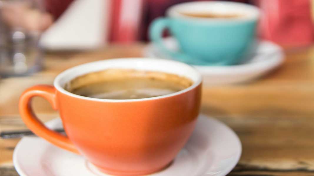 Picture of coffee cups and saucers resting on wooden table top